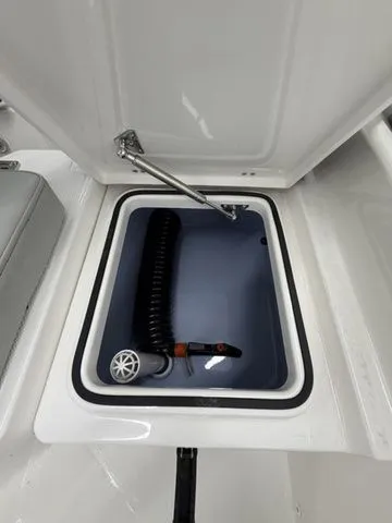 Slide: The Image of An open storage compartment on a 2026 Bay Rider 2260 FS boat with a hose inside. - 15