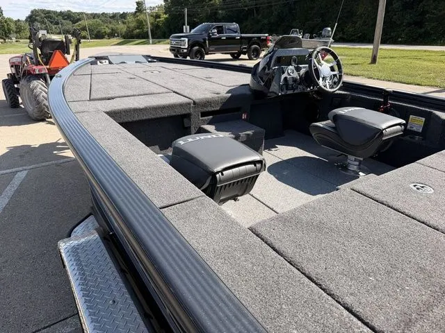 Slide: The Image of The image shows a Lund 1875 Pro-V Bass XS boat on a trailer. It features a spacious deck and helm. - 12
