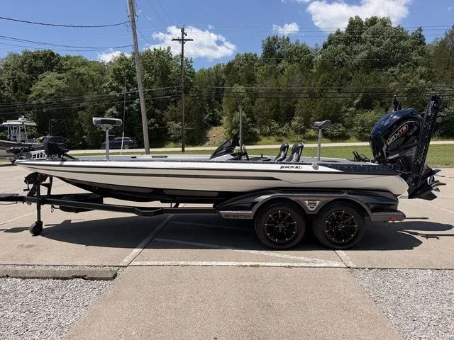 Slide: The Image of A 2024 Skeeter FXR21 Limited on a trailer, parked on a concrete lot with trees in the background. - 17