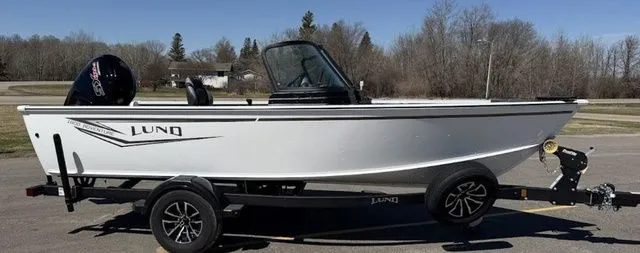 The Image of A white 2027 Lund 1800 Adventure Sport boat on a trailer, parked in a lot. - 1