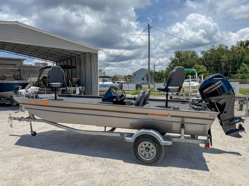 Slide: The Image of A gray 2022 Lowe Legacy boat on a trailer, parked in front of a shed. - 4