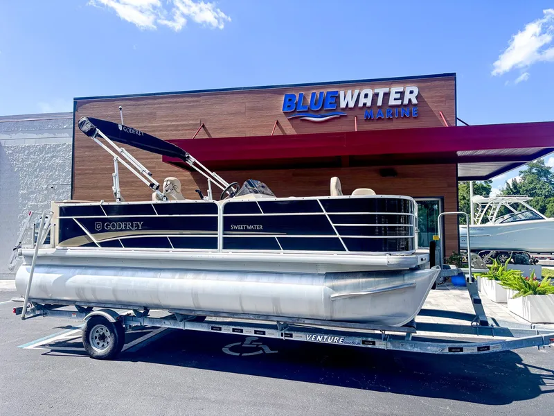 The Image of A 2022 Godfrey Sweetwater 2086 F pontoon boat on a trailer in front of a building. - 1