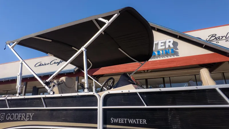 Slide: The Image of A Godfrey Sweetwater 2086 F pontoon boat with a sunshade, parked in front of a building. - 5