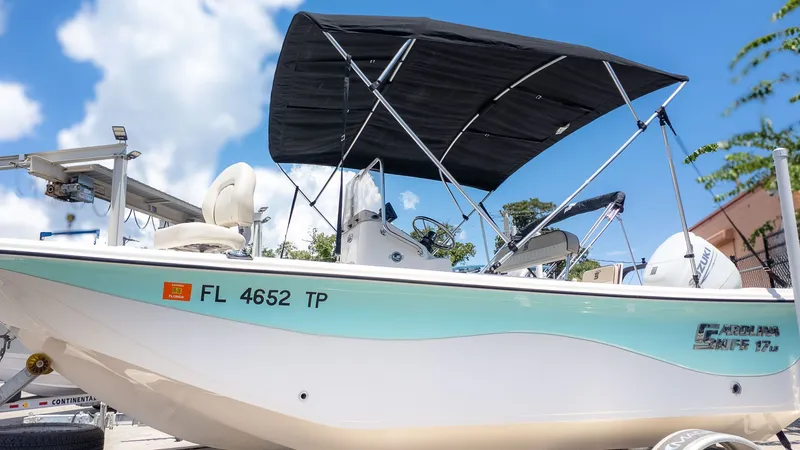 Slide: The Image of A 2023 Carolina Skiff 17 LS with a Bimini top, on a trailer, against a blue sky. - 22