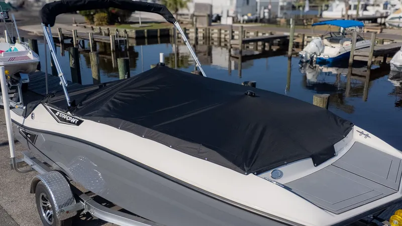 Slide: The Image of A 2027 Starcraft J7 JET Standard with a black cover, on a trailer by the water. - 18
