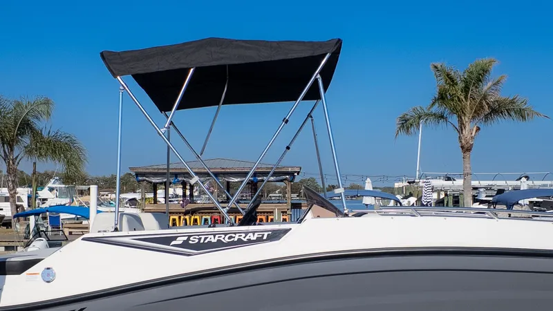 Slide: The Image of A Starcraft J7 JET Standard boat with a sunshade, docked with palm trees in the background. - 17