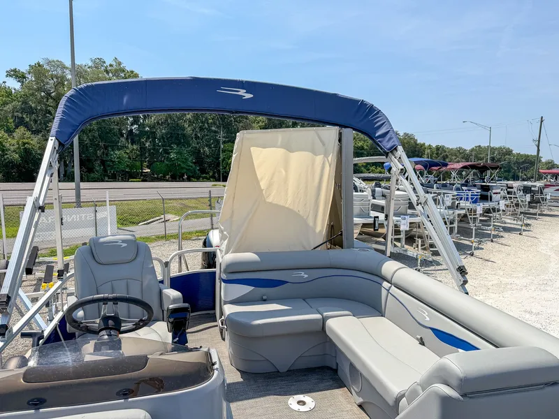 Slide: The Image of Bennington 20 SVL pontoon boat with blue accents and sunshade, parked on a lot. - 8