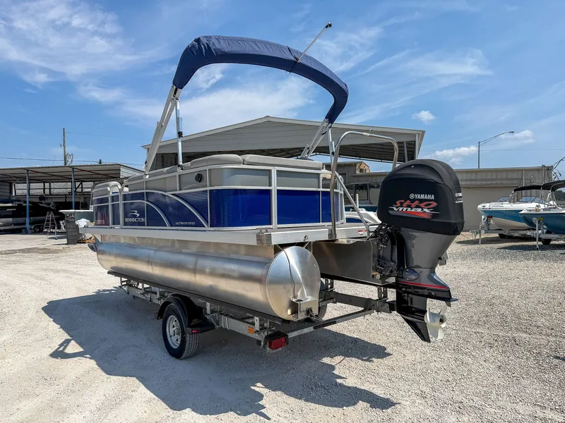 The Image of A 2024 Bennington 20 SVL pontoon boat on a trailer in a storage area. - 1