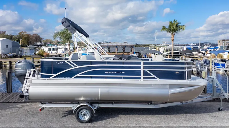 Slide: The Image of Bennington 20 S Fishing pontoon boat at dock with palm trees in the background. - 22