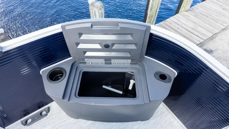 Slide: The Image of A gray storage compartment with an open lid on a boat, surrounded by blue water and a dock. - 15