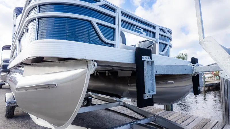 The Image of A Bennington 20 S Fishing pontoon boat on a trailer by the water. - 1