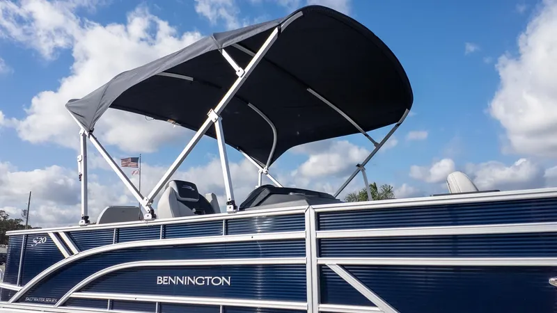 Slide: The Image of A Bennington 20 S Fishing pontoon boat with a blue hull and black bimini top under a blue sky. - 22