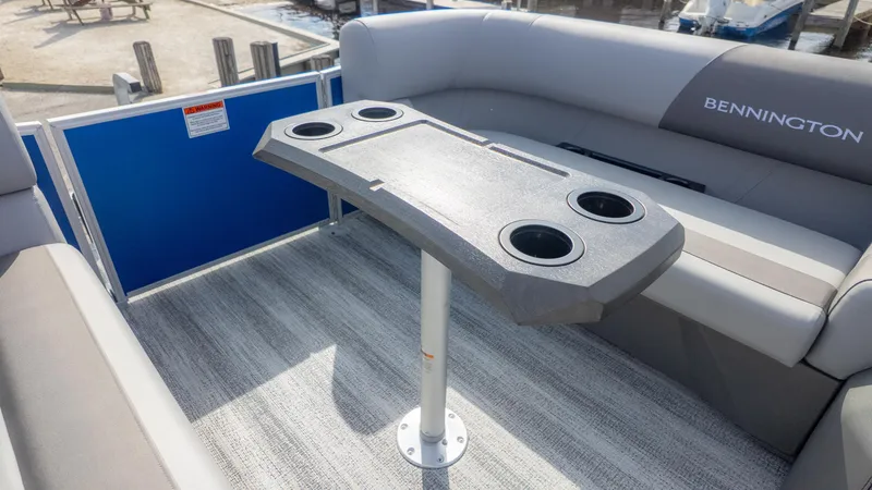 Slide: The Image of Interior of a Bennington 20SSRSE pontoon boat with gray seating and a table with cup holders. - 11