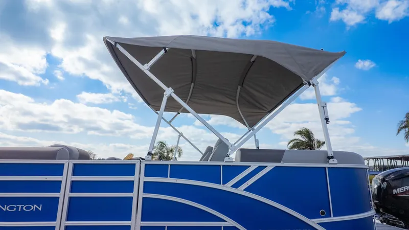 Slide: The Image of A Bennington 20SSRSE pontoon boat with a blue hull and gray sunshade under a cloudy sky. - 20