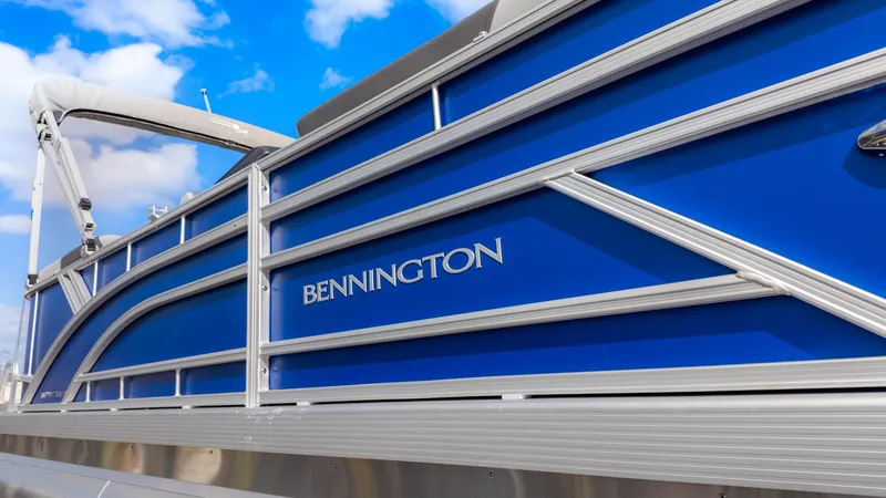 Slide: The Image of Close-up of a blue Bennington pontoon boat with silver details against a blue sky. - 5