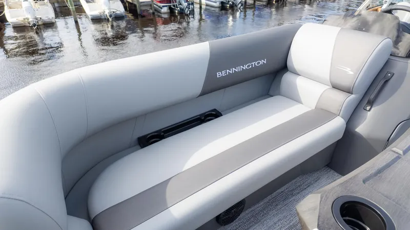 Slide: The Image of The image shows a luxurious gray seating area on a Bennington boat by the water. - 10
