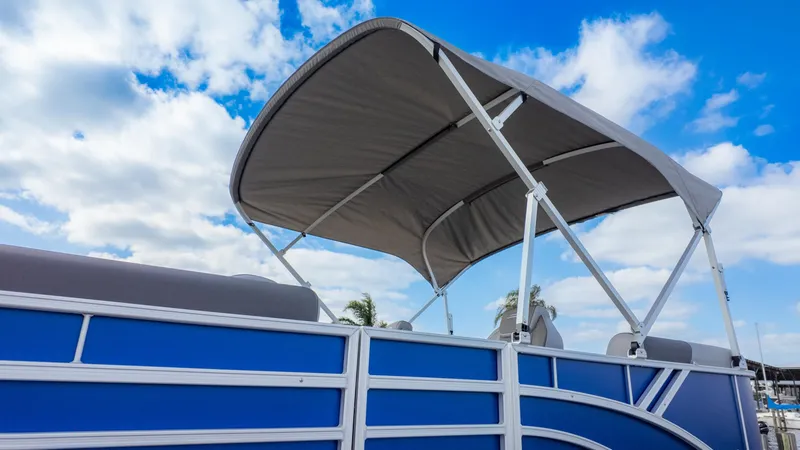 Slide: The Image of A Bennington 20SSRSE pontoon boat with a blue hull and gray canopy under a blue sky. - 17