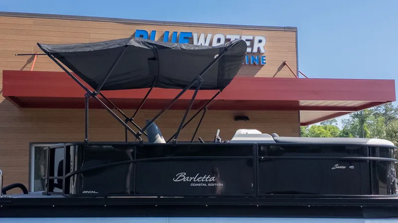 The Image of A Barletta Sanza 20L pontoon boat with a black canopy in front of a building. - 1