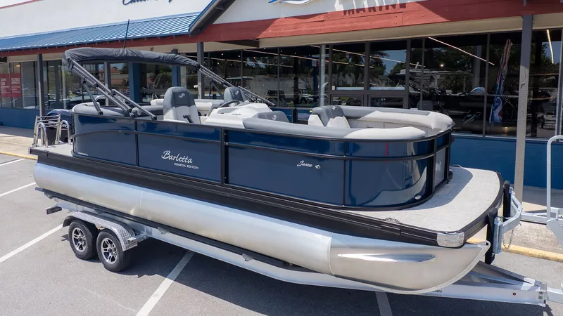 Slide: The Image of A 2026 Barletta SANZA 22QC pontoon boat on a trailer in front of a building. - 3