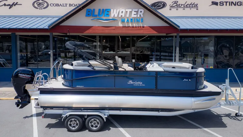 Slide: The Image of The image shows a Barletta SANZA 22QC pontoon boat on a trailer in front of a boat dealership. - 32