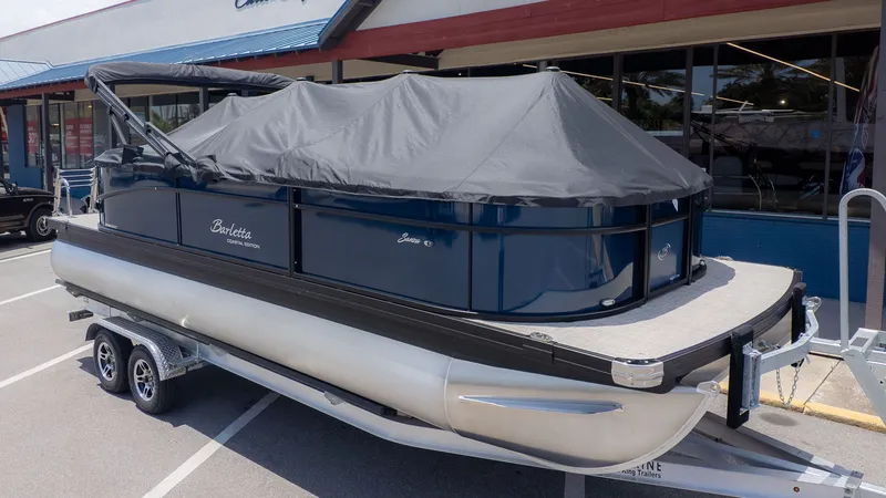 The Image of A Barletta SANZA 22QC pontoon boat on a trailer, covered with a protective tarp. - 1