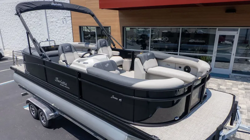 The Image of A sleek Barletta SANZA 22QC pontoon boat on a trailer, ready for adventure. - 1