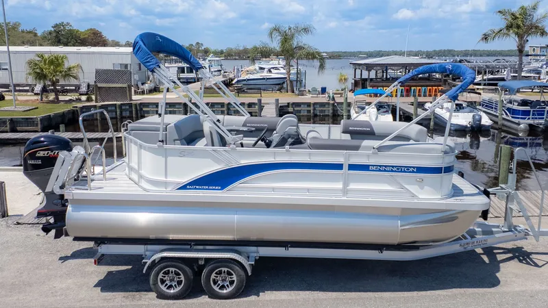 Slide: The Image of 2026 Bennington 20 S Cruise pontoon boat at dock with blue accents and covered seating area. - 17