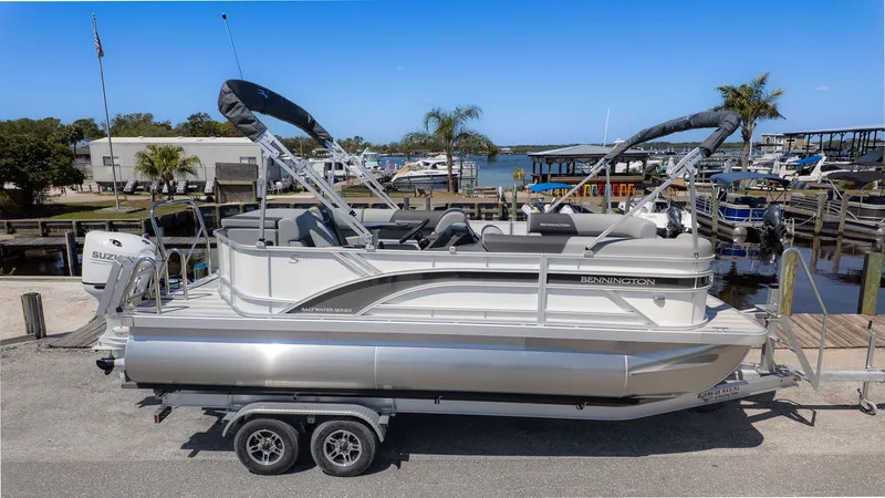 Slide: The Image of A Bennington 20 S Cruise pontoon boat on a trailer, surrounded by a marina with palm trees. - 18
