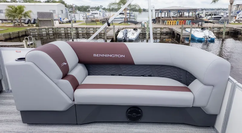 Slide: The Image of Bennington 21 S Fish and Cruise 2026: Sleek gray and brown sofa on a boat, with marina in the background. - 9