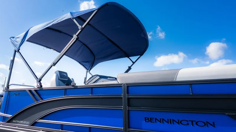 Slide: The Image of Bennington 21 S Cruise pontoon boat with blue canopy and sleek lines against a blue sky. - 21