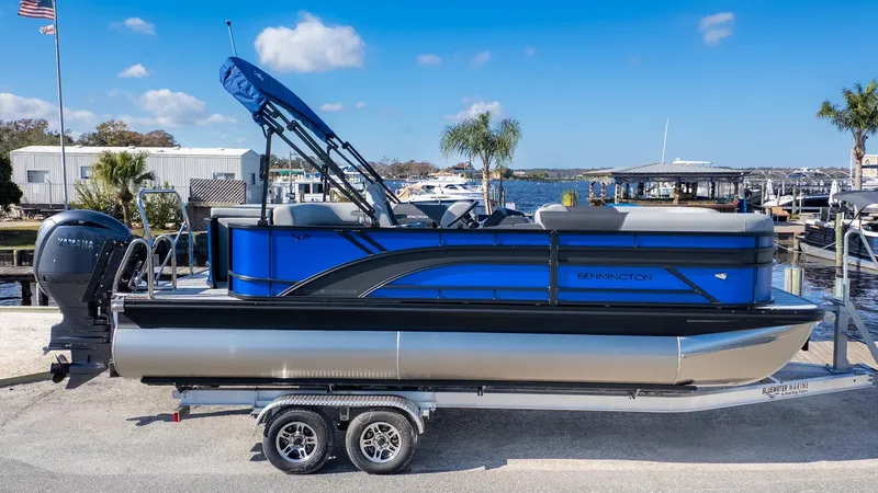 Slide: The Image of A Bennington 21 S CRUISE pontoon boat on a trailer, featuring a blue canopy and outboard motor. - 20