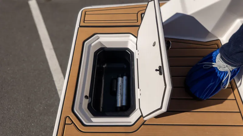 Slide: The Image of An open storage compartment on a boat with wooden flooring and a person in blue shoe covers. - 6