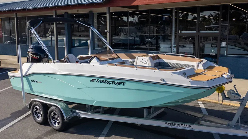 Slide: The Image of A 2026 Starcraft SVX 211 OB boat on a trailer in front of a building. - 23