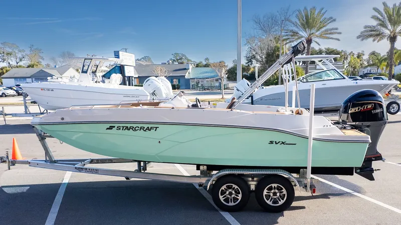 The Image of A 2026 Starcraft SVX 211 OB boat on a trailer in a sunny parking lot. - 1