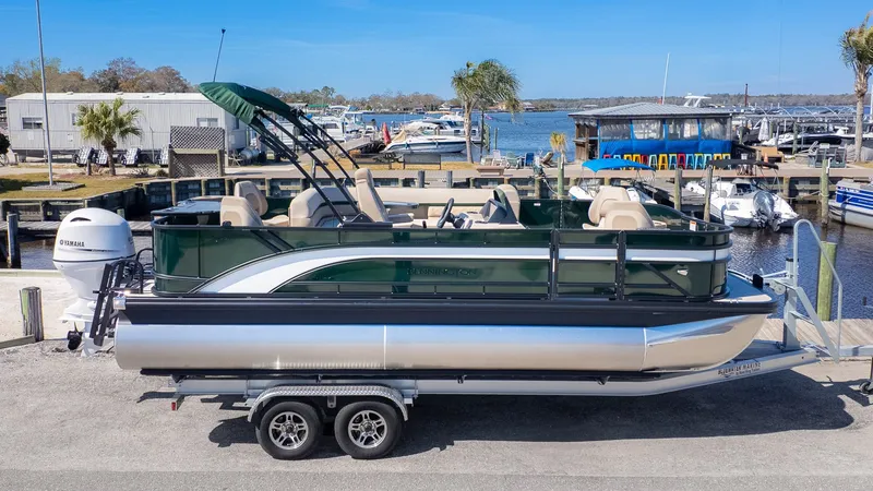 Slide: The Image of A Bennington 21 S Fishing pontoon boat on a trailer, with a green canopy, in a marina. - 19