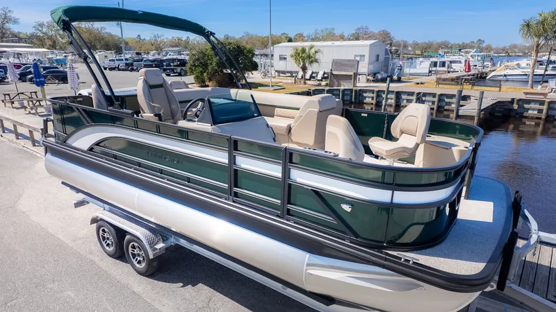 Slide: The Image of 2026 Bennington 21 S Fishing pontoon boat on shore with green hull and beige interior. - 21