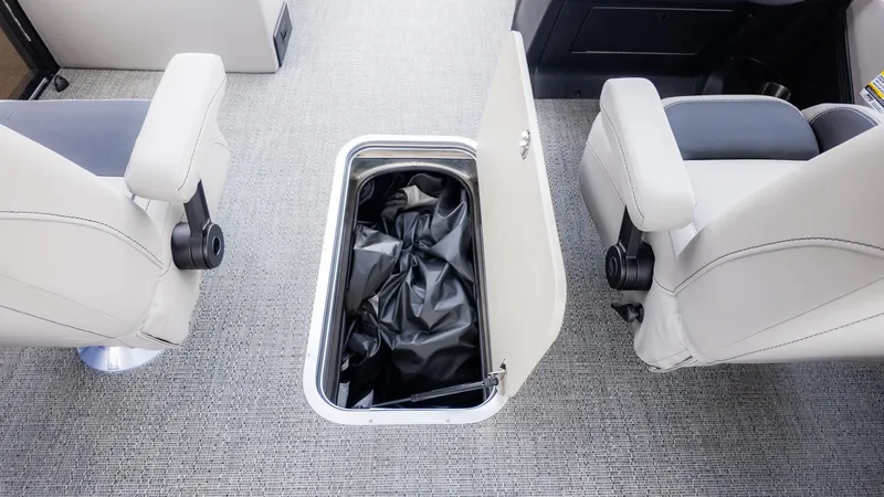 Slide: The Image of Interior of a Barletta ARIA 22QC with an open storage compartment between two seats. - 10