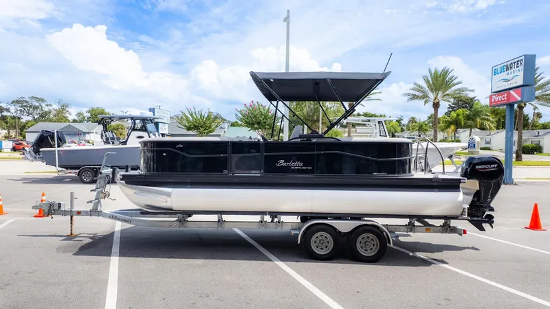 Slide: The Image of A Barletta ARIA 22QC pontoon boat on a trailer, parked in a lot under sunny skies. - 4
