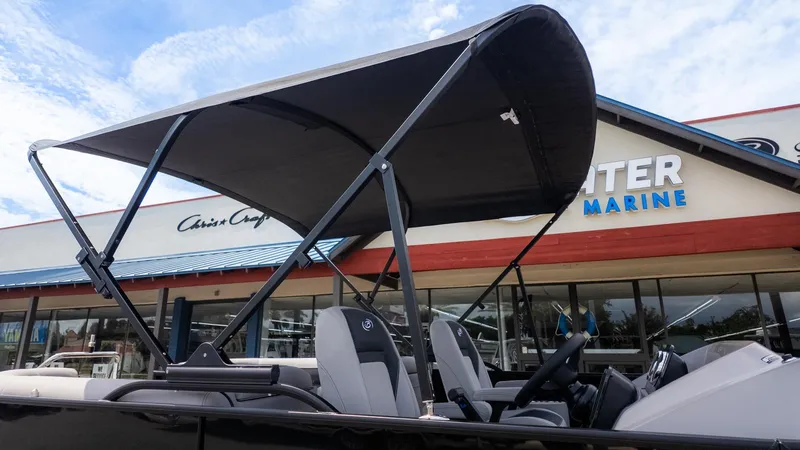 The Image of The image shows a Barletta ARIA 22QC boat with a black sunshade, parked in front of a store. - 1