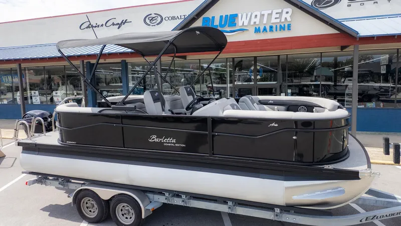 Slide: The Image of Barletta ARIA 22QC pontoon boat on a trailer outside a marine dealership. - 23