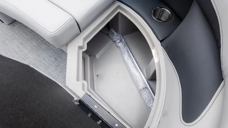 Slide: The Image of An open storage compartment on a boat with a gray interior and a cup holder. - 18