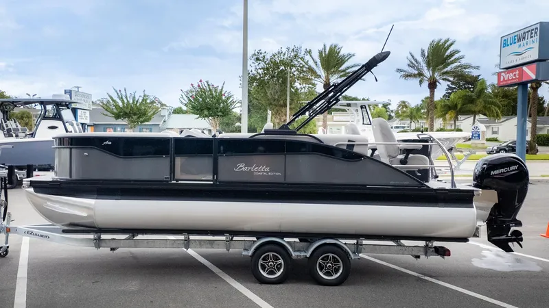The Image of A 2026 Barletta Aria A22CC pontoon boat on a trailer in a parking lot. - 1