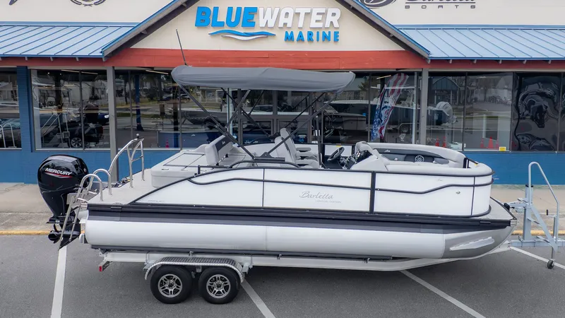 Slide: The Image of A Barletta ARIA 22UC pontoon boat on a trailer in front of a blue building. - 27