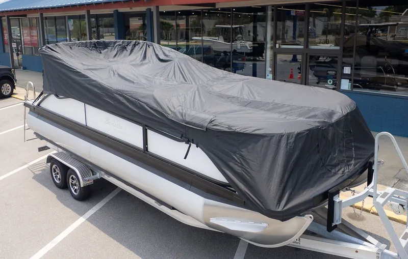 Slide: The Image of A Barletta ARIA 22UC pontoon boat with a cover on a trailer in front of a building. - 27