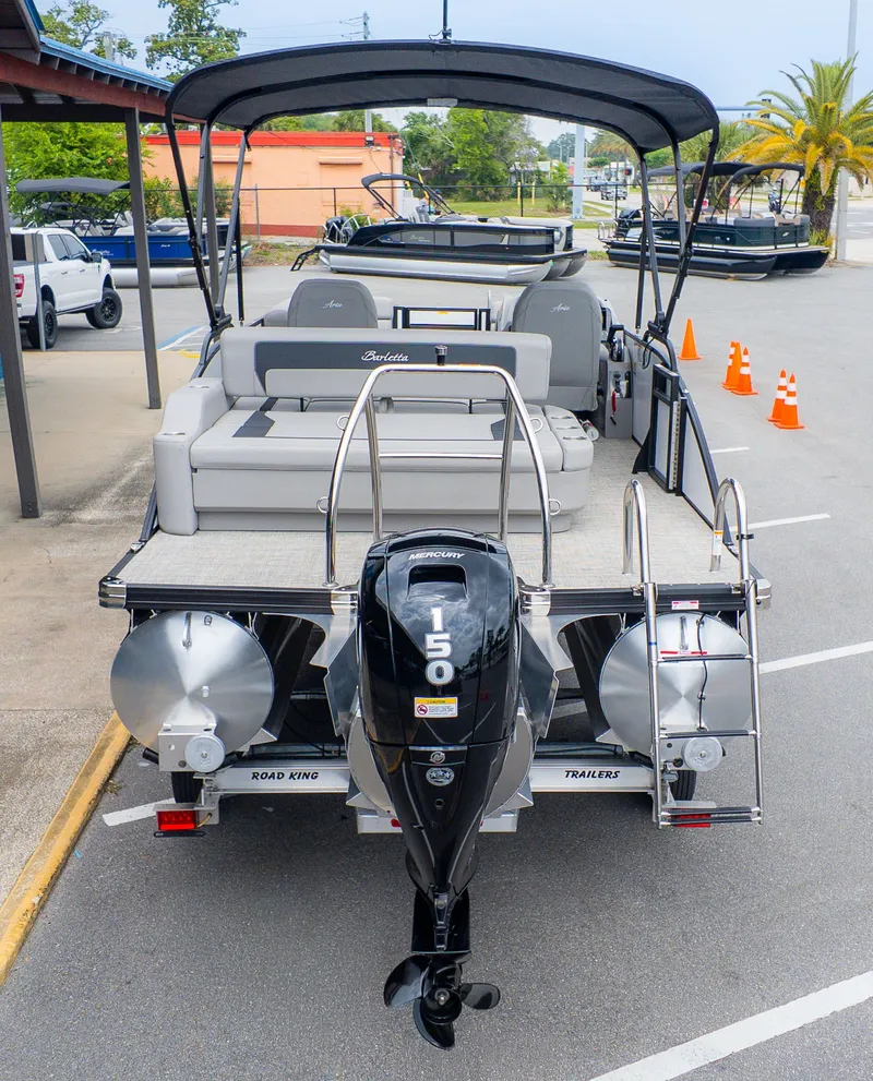 Slide: The Image of The image shows a Barletta ARIA 22UC pontoon boat with a 150 HP engine, sitting on a trailer. - 4