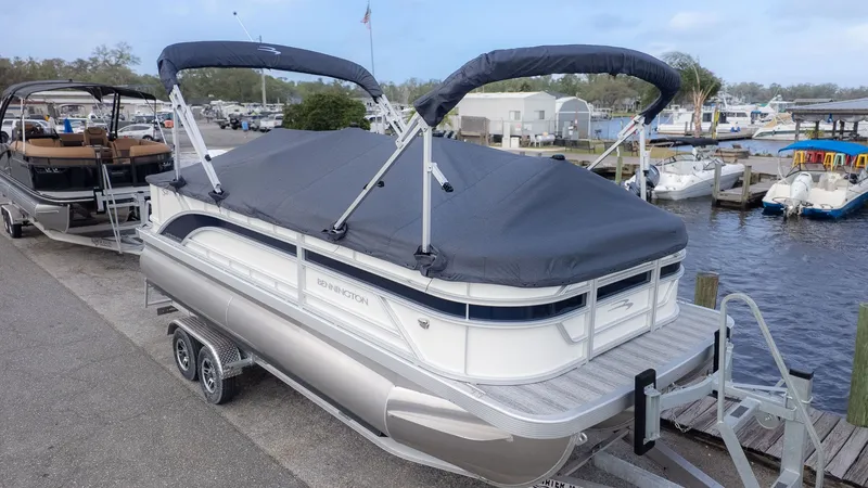 Slide: The Image of A Bennington pontoon boat with a gray cover is docked. Other boats are visible in the background. - 23