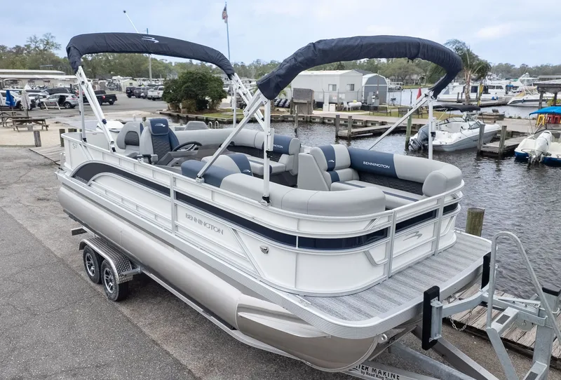 The Image of A Bennington pontoon boat, model 21 S Fish and Cruise, sits on a trailer at a marina. - 1