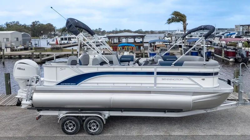 Slide: The Image of 2026 Bennington 21 S Fish and Cruise pontoon boat on a trailer at the dock. - 21