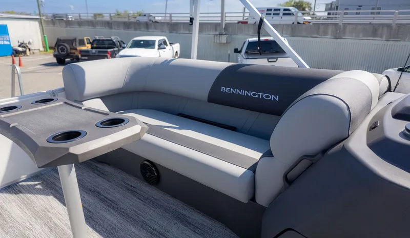 Slide: The Image of Bennington 21 S Swingback 2026 with gray upholstered sofa and table with cup holders. - 14