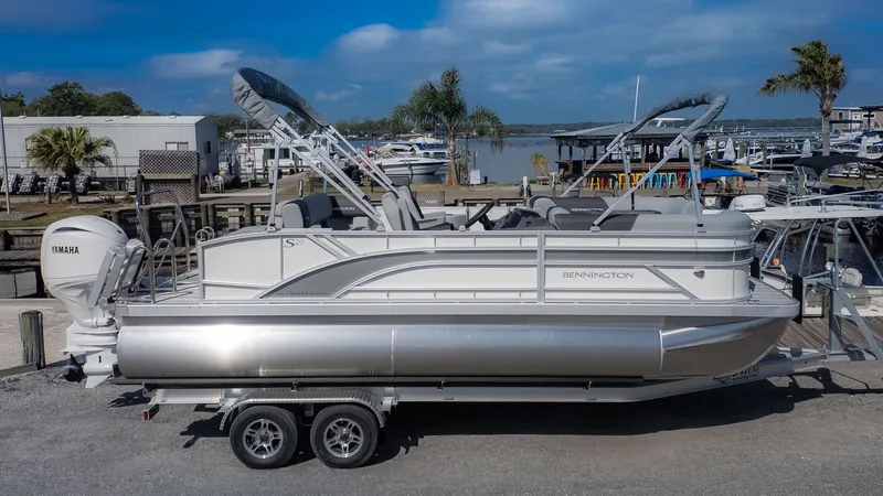 Slide: The Image of A Bennington 21 S Swingback pontoon boat on a trailer in a marina area. - 20